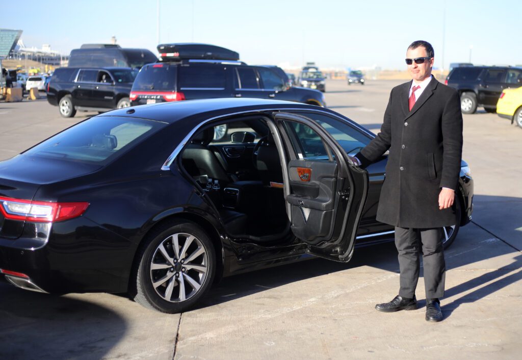 Chauffeur opens car's rear door