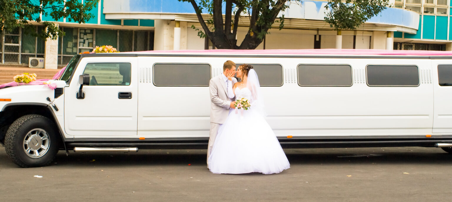 Portrait of beautiful happy wedding couple, Just Married opposite limousine