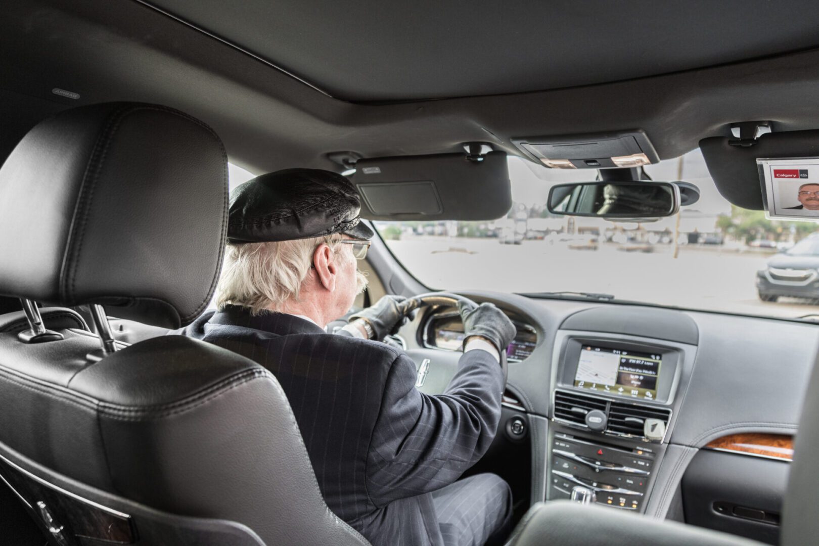 A man driving a van with other cars visible from the front window