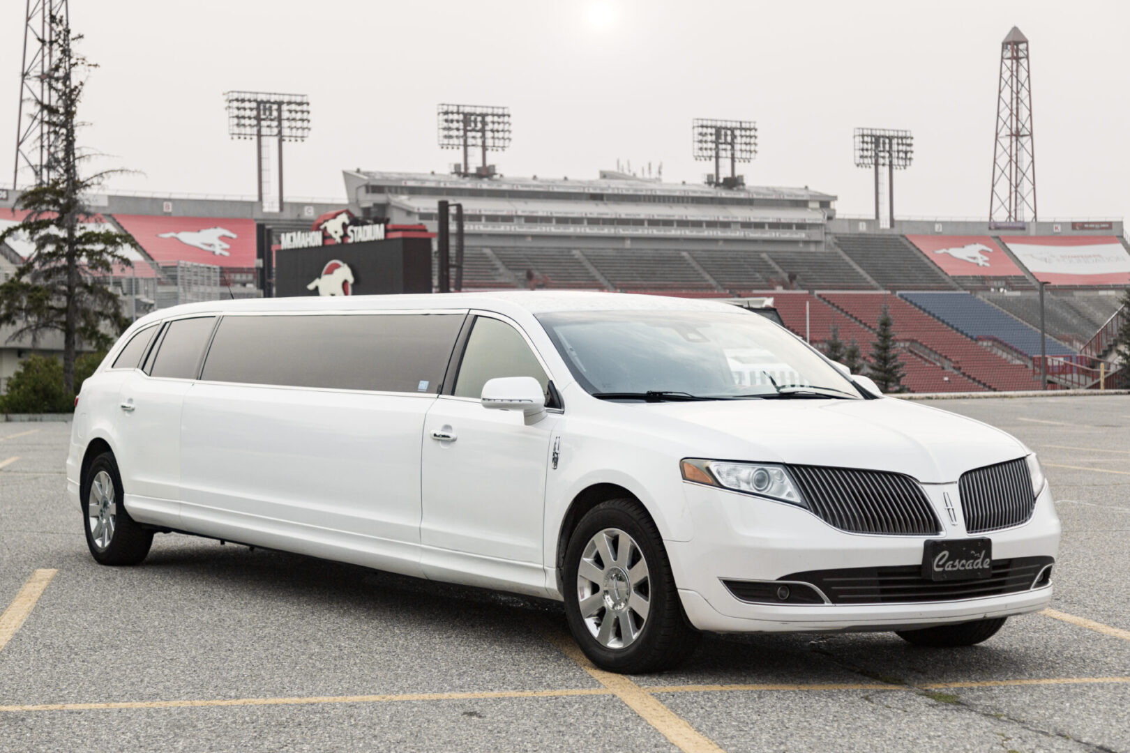 A white stretch limo parked in front of an empty stadium.