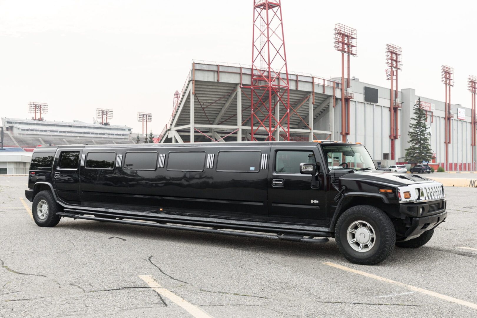 A black hummer limousine parked in front of a stadium