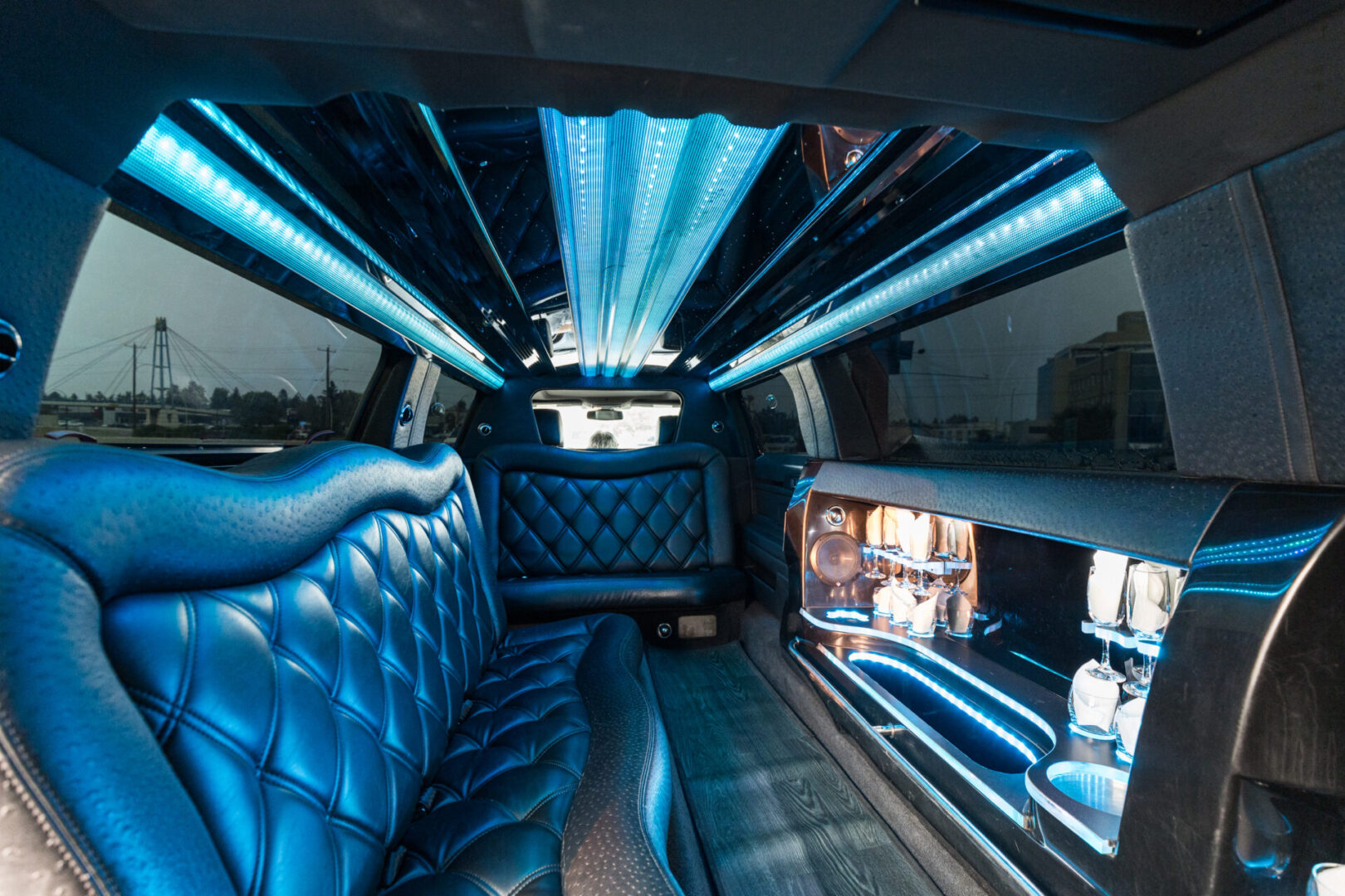 A limo with blue leather seats and lights on the ceiling.
