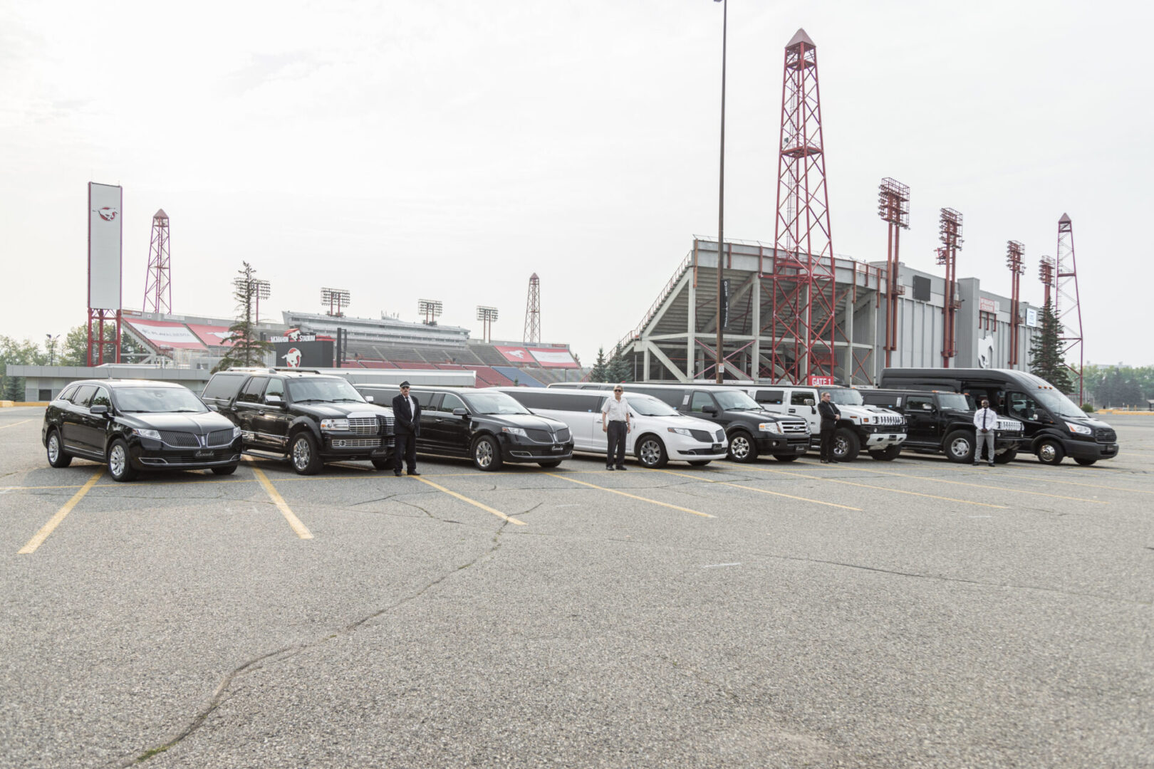 A group of cars parked in a parking lot with a stadium in the background