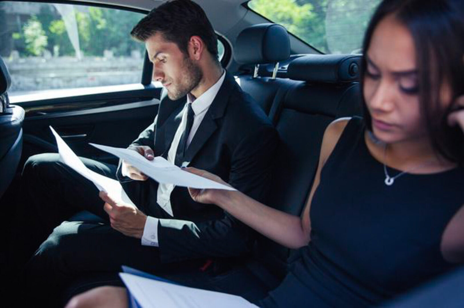 Business professionals working in the backseat of a luxury car