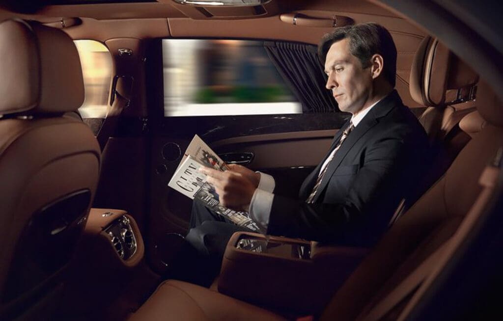 Businessman reading a newspaper in a luxury car