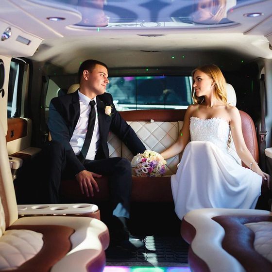 A man and woman sitting in the back of a limo.